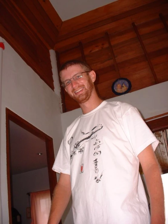 man with glasses standing in room with a clock on wall