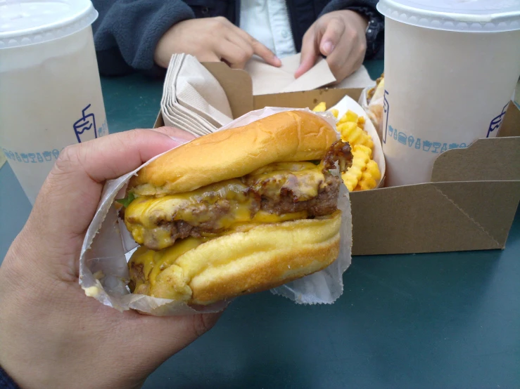 a person is holding up a large hamburger