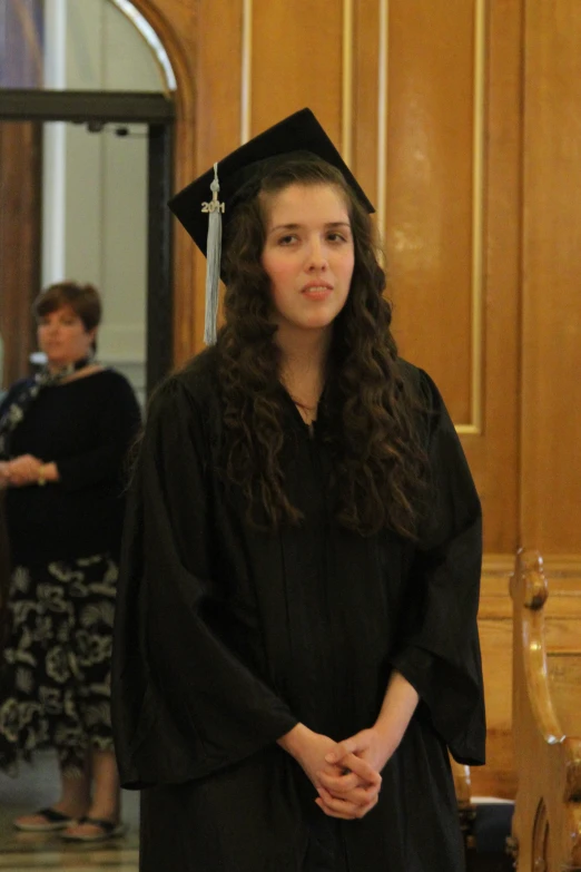 young female student in graduation gown and hat looking forward