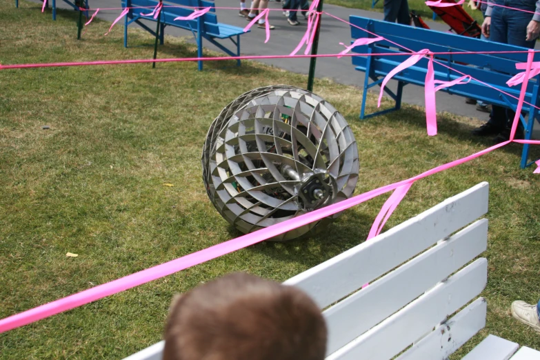 an open circular object on grass next to a blue bench