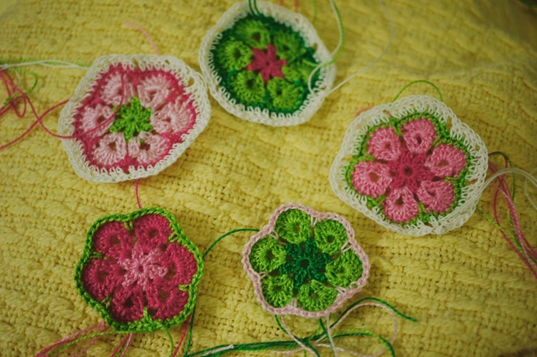 four crocheted flower pieces are sitting on a blanket