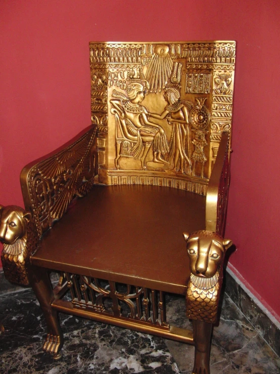 a large gold and wooden carved chair in front of a wall