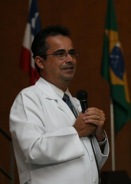 a man in a white lab coat speaking into a microphone