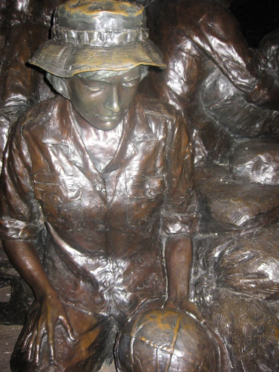 a statue of a man holding a ball wearing a sun hat