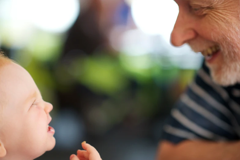 an elderly man holding his hand next to a baby