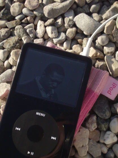 an ipod and mp3 player lying on some rocks