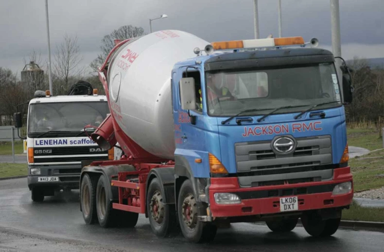 a concrete truck is towing a smaller truck on a road