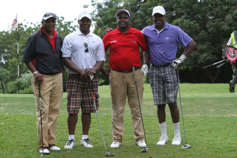 four men stand together in a golf field