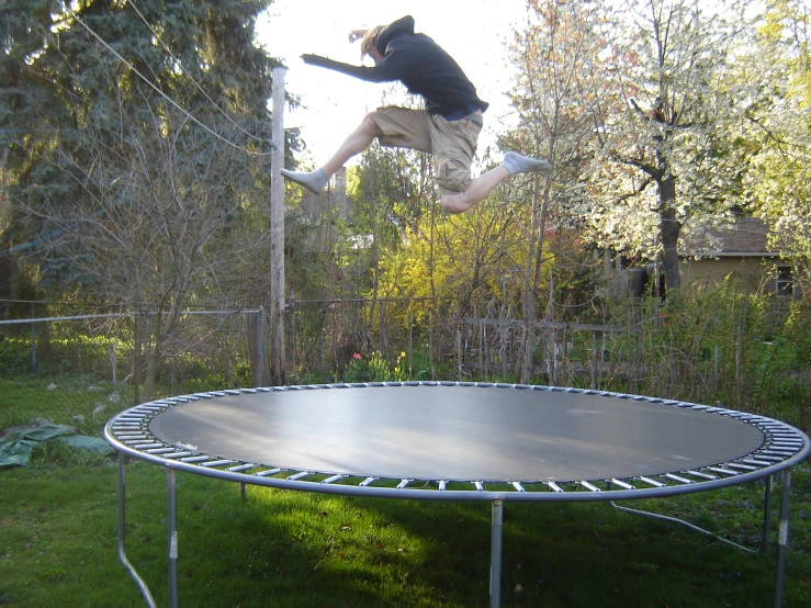 a man jumps high in the air with a toy above an empty trampoline