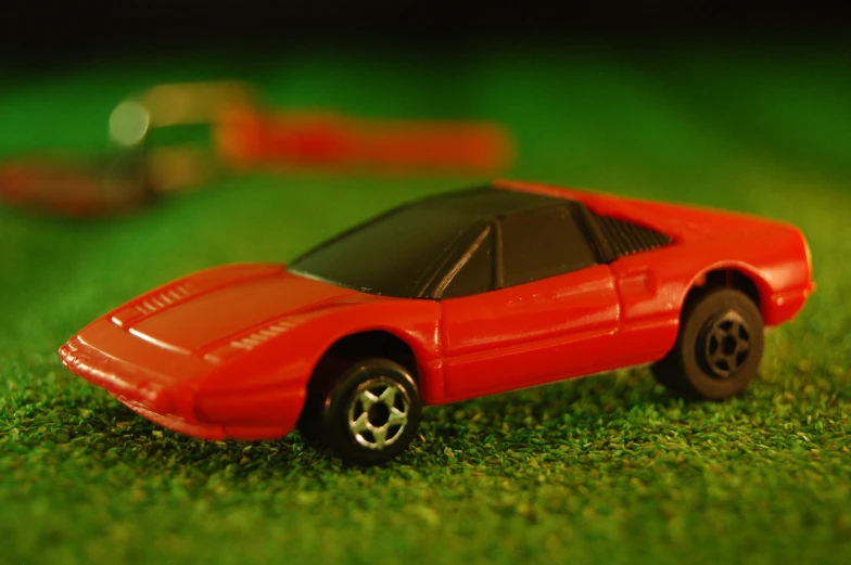 a red toy car sitting on top of grass