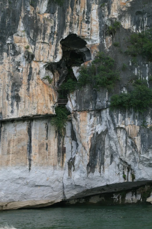 a rock cliff with a wooden staircase and an opening at the top