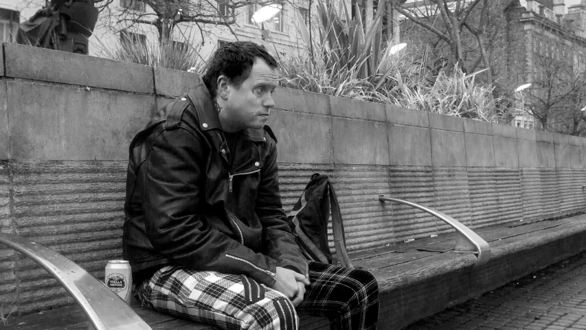 a man sits in a public area on a bench