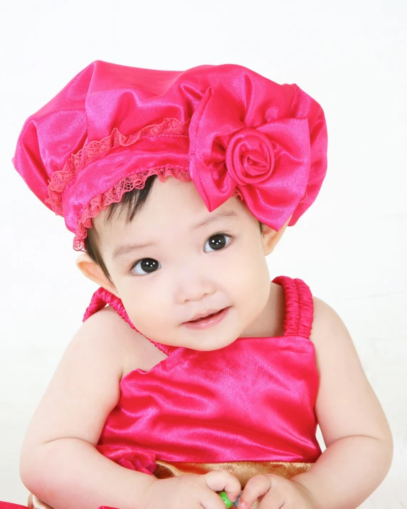 a young child wearing a pink dress and hat