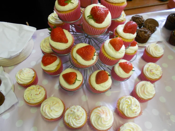 cupcakes are arranged in a pyramid, with strawberries atop them