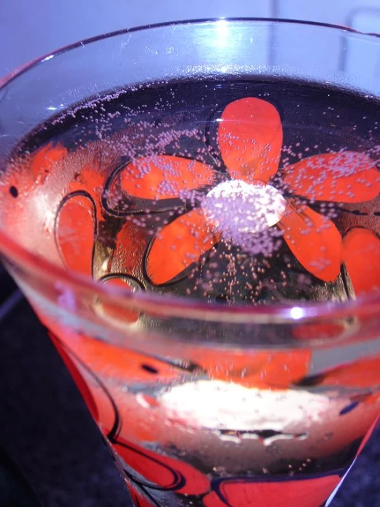 a glass of water with orange flowers and bubbles in it