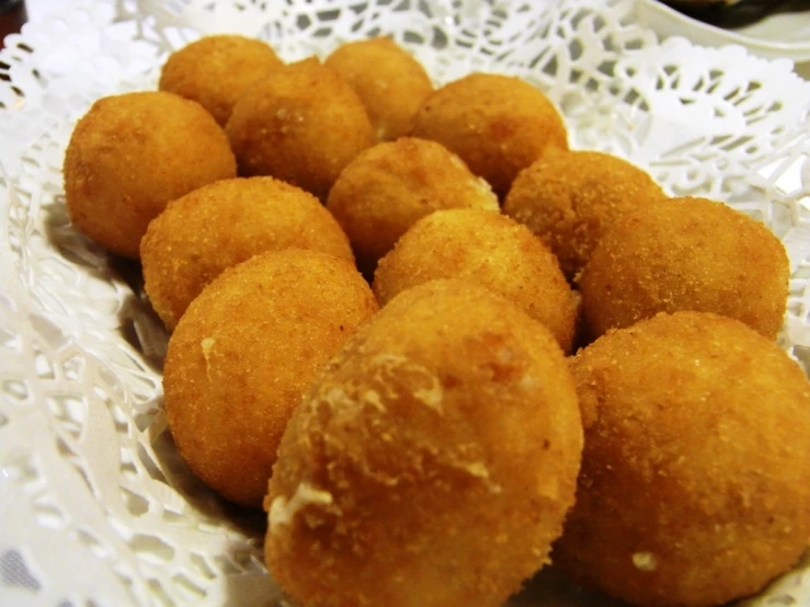 a bunch of small balls of fried food sitting on a doily
