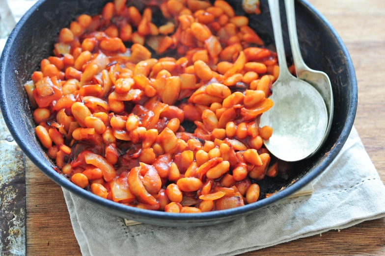 some food is in a black pan with silver spoon