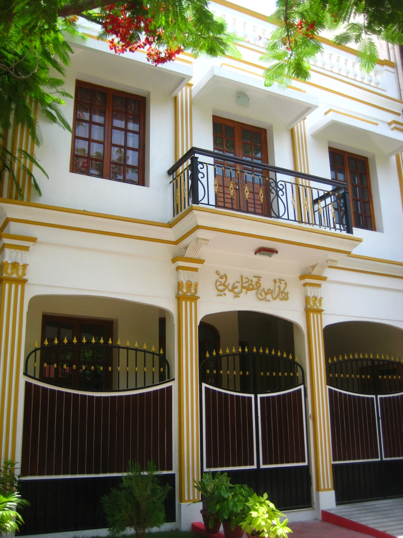 a large white building has black wrought iron fencing