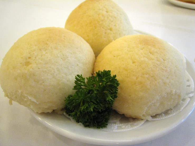 three rolls and a green leaf on a plate