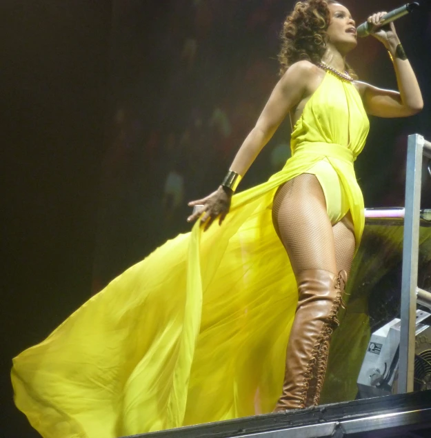 a  lady in yellow is singing into a microphone