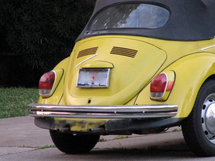 a bright yellow volkswagen type car sitting on the sidewalk