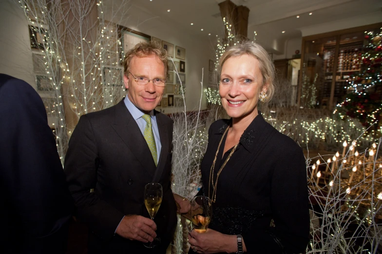 two people standing next to each other near christmas trees