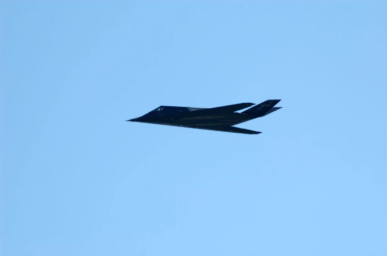 a jet flies against a blue sky with its tail extended