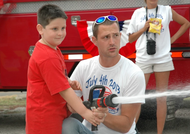 a boy and man stand beside a fire truck