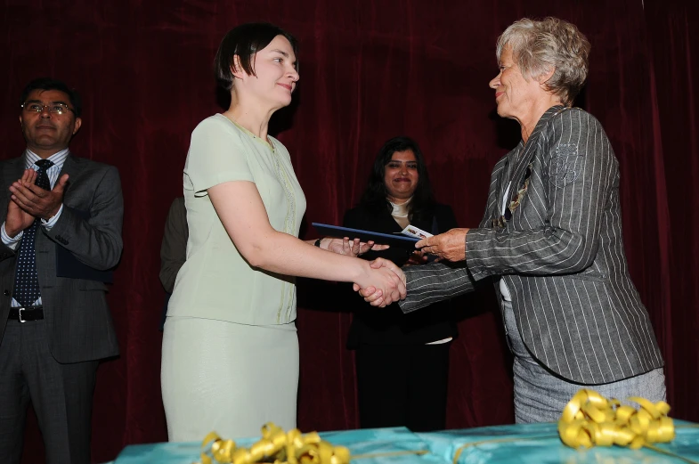 an elderly woman is shaking hands with a woman