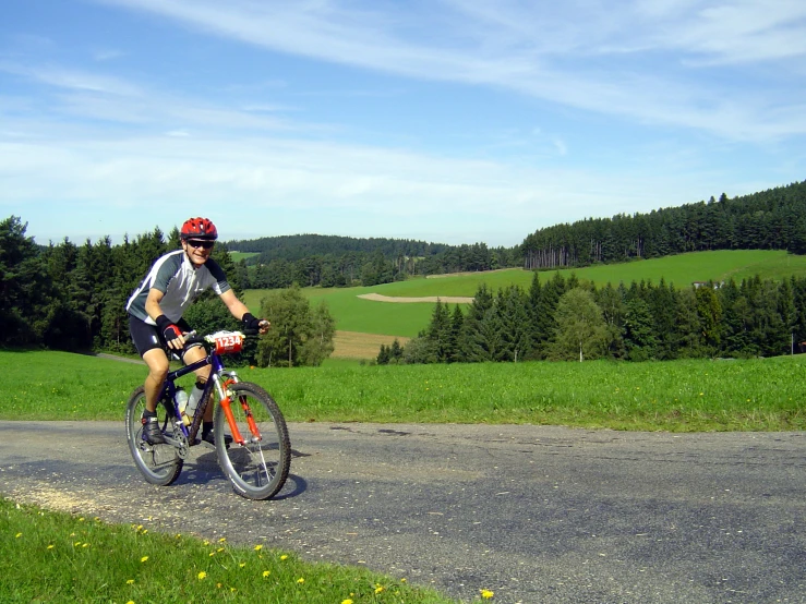 a man riding his bike on the side of a country road