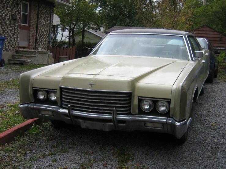 old car sitting in a driveway near some houses