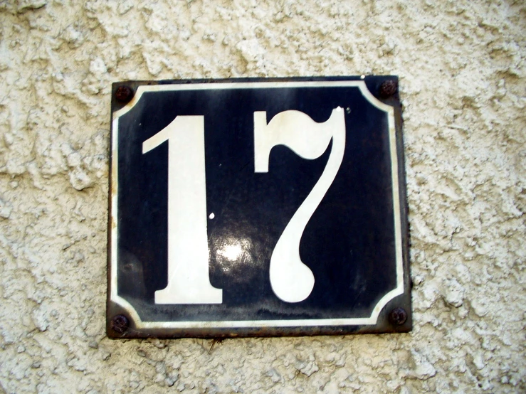 a sign that says 17th on it sitting against the side of a wall