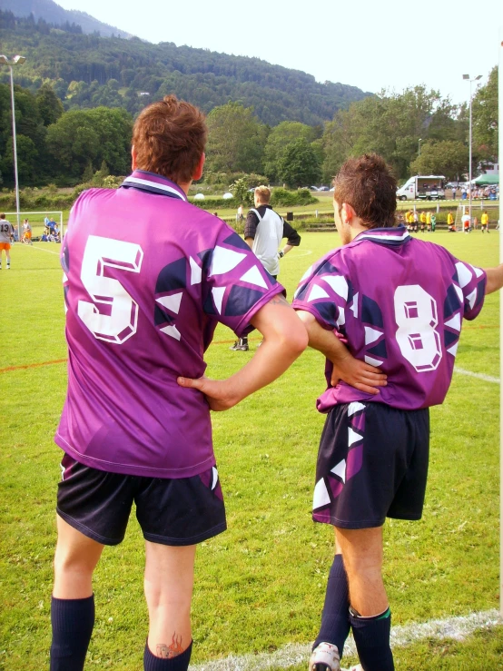 two boys in purple uniforms playing soccer on the field