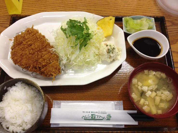 a white plate with rice, meat and sauce