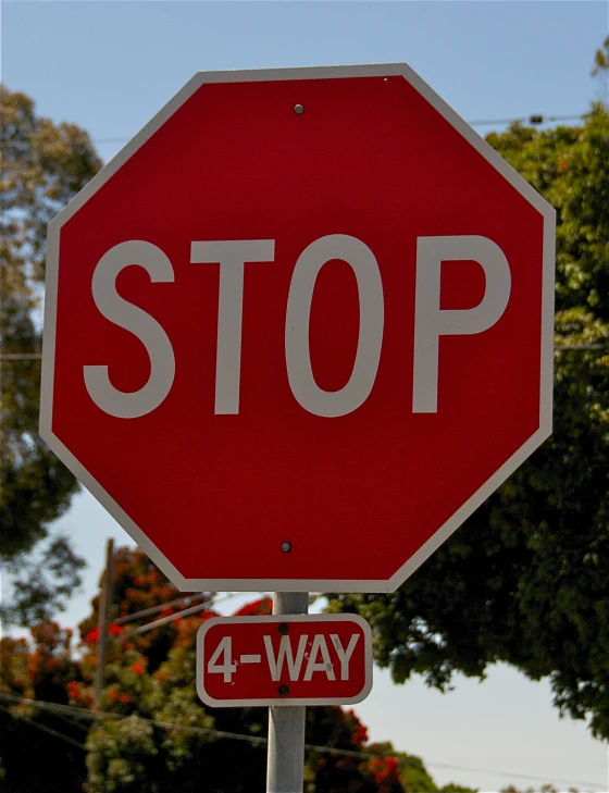 a four way stop sign under a blue sky