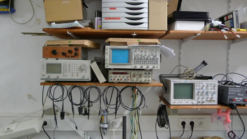 various electronic devices on shelves with boxes and papers