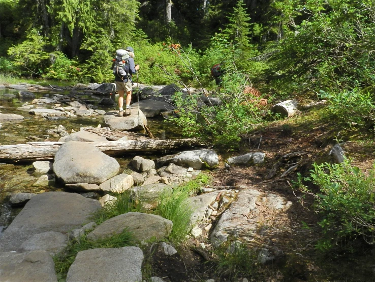 a hiker crossing rocks along the water's edge