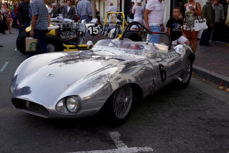 people are lined up on the street to see and admire old fashioned cars