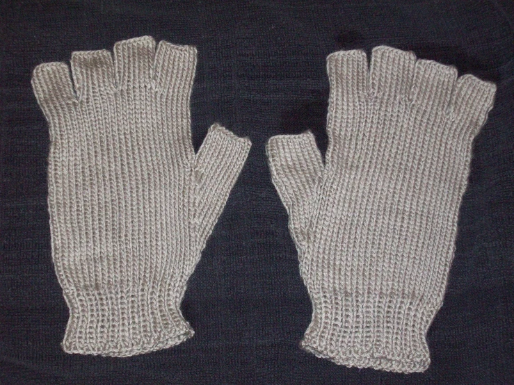two gloves on a black surface one is gray and the other has white knit