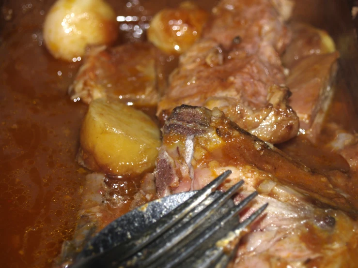 a fork laying in meat stew with potatoes