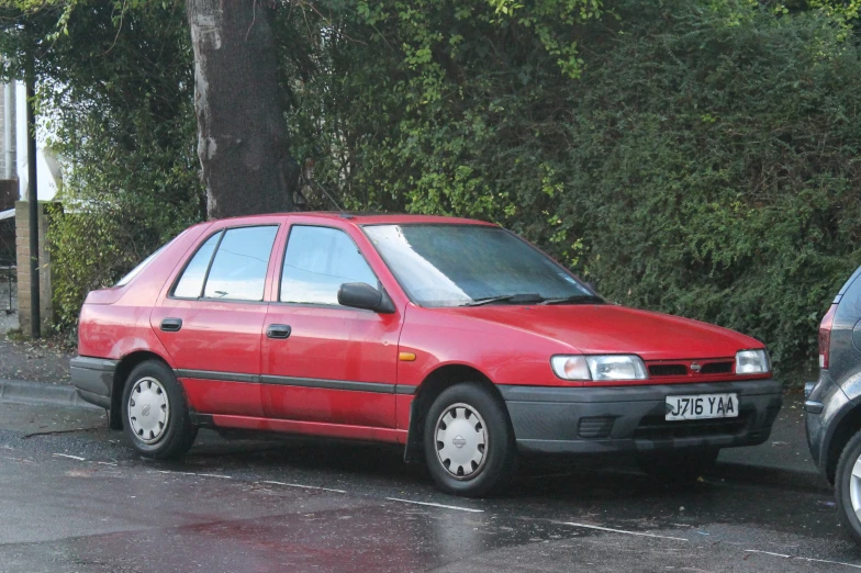 a small red car sits in a parking space next to another car