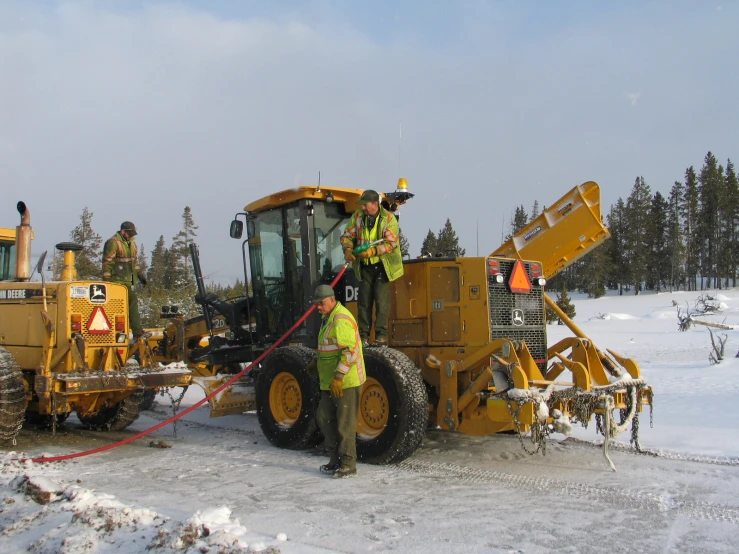 men with yellow equipment in snowy area near machinery