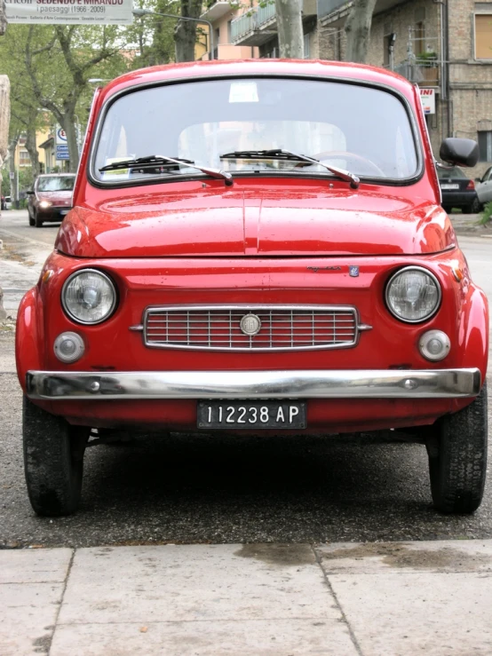 a small red car is on the curb