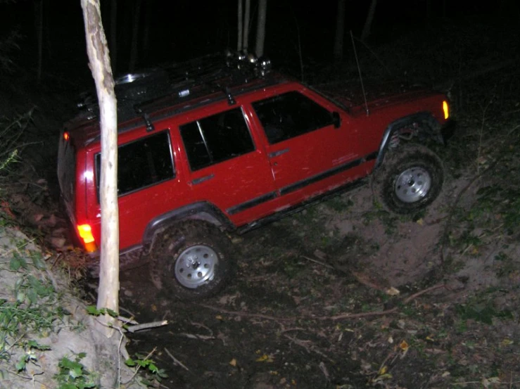 a red suv is in the forest at night