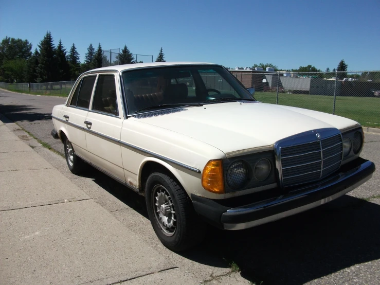 a white mercedes parked next to a park