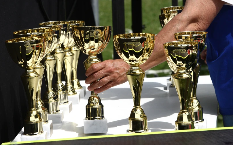 many golden cups are lined up on a table