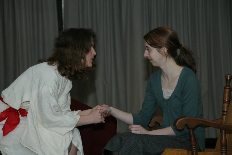 a lady sitting on a chair facing a lady in the other hand