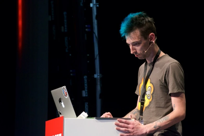 a man standing on stage looking at a laptop computer