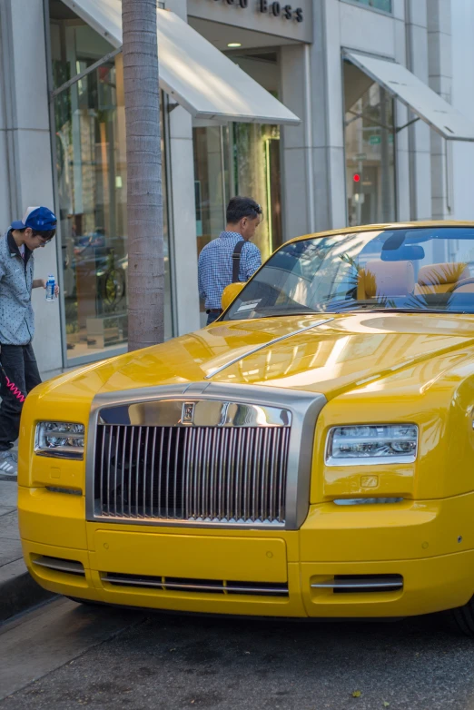 the yellow limousine has a bunch of people standing next to it