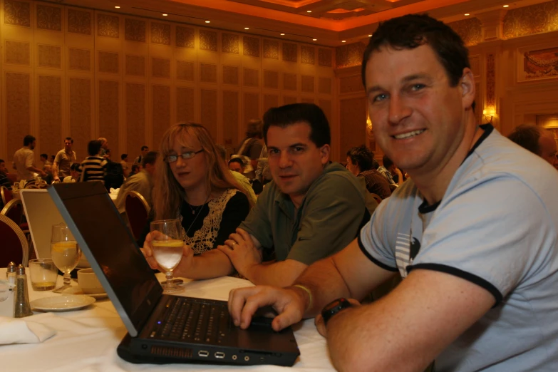 people at a dinner table having wine and a laptop